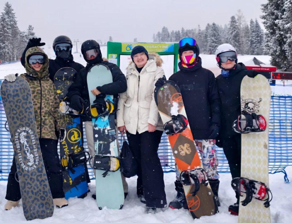 KIlkoro młodych sportowców w strojach narciarskich pozujących do grupowego zdjęcia.